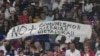 Asistentes a la semifinal del Clásico Mundial de Béisbol entre Cuba y EEUU levantan un cartel que reza "No más comunismo, miseria, dictadura!!". (AP/Marta Lavandier)