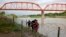 Tres migrantes cubanos llegan a suelo estadounidense tras cruzar el Río bravo en Eagle Pass, Texas, el 22 de mayo de 2022. (AP Foto/Dario Lopez-Mills)
