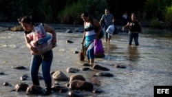 Un grupo de personas cruza el río Táchira, que divide a Venezuela y Colombia en el sector "La Invasión", en la ciudad de San Antonio (Venezuela)