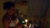 Una mujer prepara unos platos de comida en la cocina, iluminada con velas, en un apagón en el barrio de Alamar