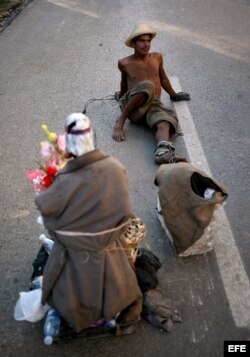 Un hombre toma un descanso mientras arrastra una piedra y una imagen de San Lázaro el domingo 16 de diciembre de 2012, durante una procesión en el Santuario de El Rincón, Cuba.