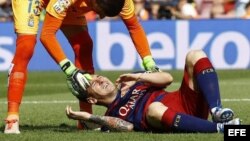 El delantero argentino del FC Barcelona Leo Messi es atendido por el portero de Las Palmas, Javier Varas, tras lesionarse.