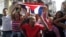 impatizantes del Gobierno cubano gritan consignas revolucionarias mientras el grupo de mujeres Las Damas de Blanco.