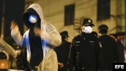 Un trabajador se coloca un mono protector antes de entrar al mercado en el que se encontró una paloma infectada con el virus de la gripe H7N9 , en Shangái, China. 