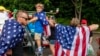 Familias portan la bandera de los Estados Unidos la víspera de la celebración por el Día de la Independencia, en Gloucester, Massachusetts, el 3 de julio de 2023. (Photo by Joseph Prezioso / AFP)