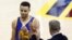 El baloncestista Stephen Curry (i) recibe instrucciones del director técnico Steve Kerr (d).