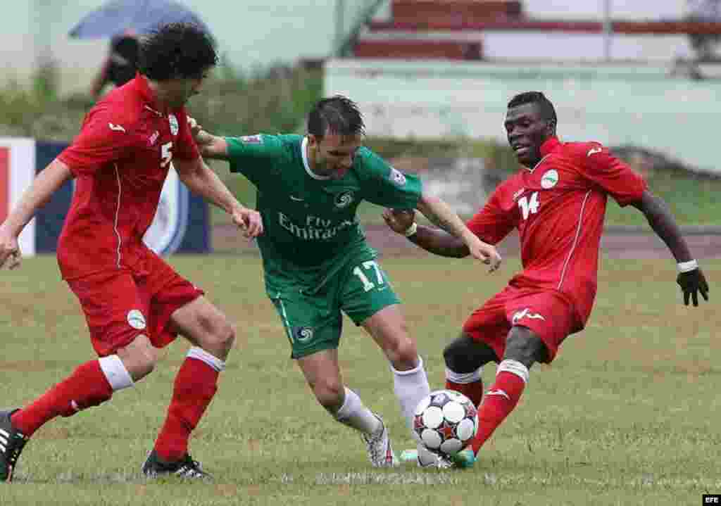 Azoye García (c) del Cosmos de Nueva York disputa el balón con Jorge Luis Clavelo (i) y Arichel Hernández (d) de la selección nacional de Cuba.